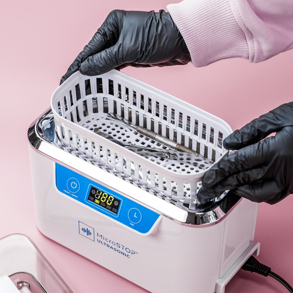 Black gloves placing nail instruments into MU-SMART ultrasonic cleaning basket